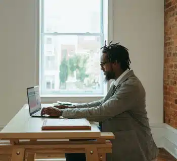 a person sitting at a desk with a laptop and papers