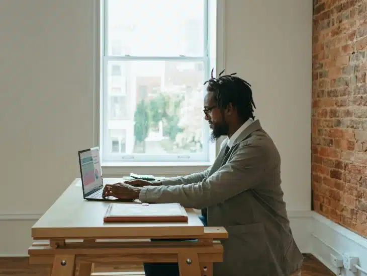 a person sitting at a desk with a laptop and papers